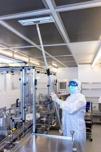 man in hazmat suit cleaning ceiling of a building with a mop