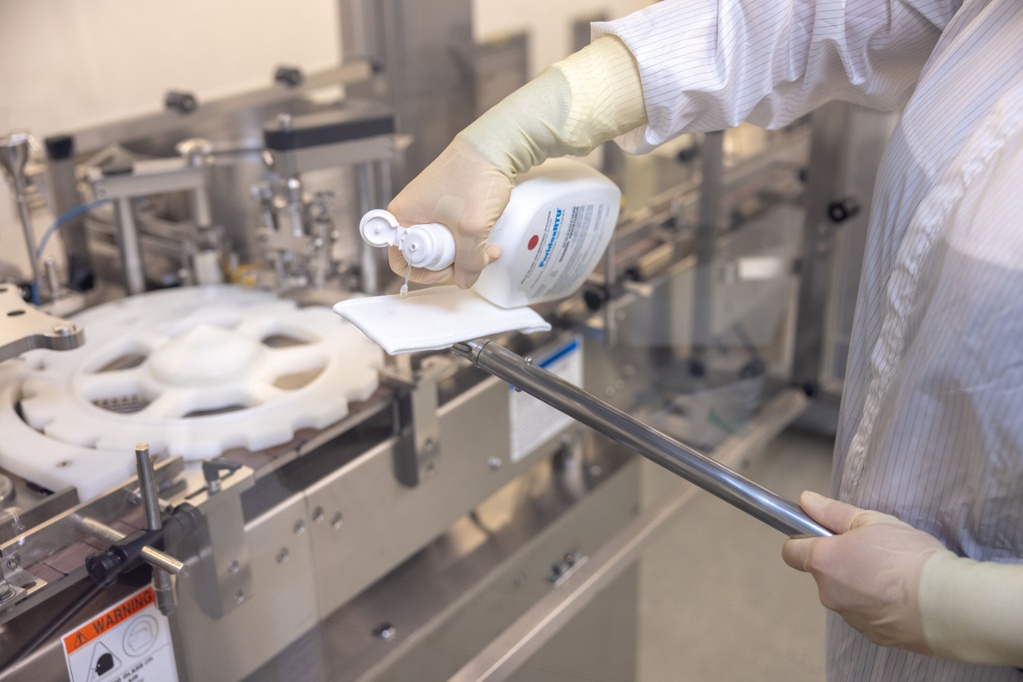 close up of person in hazmat suit pouring cleaning solution on cleaning swiffer mop