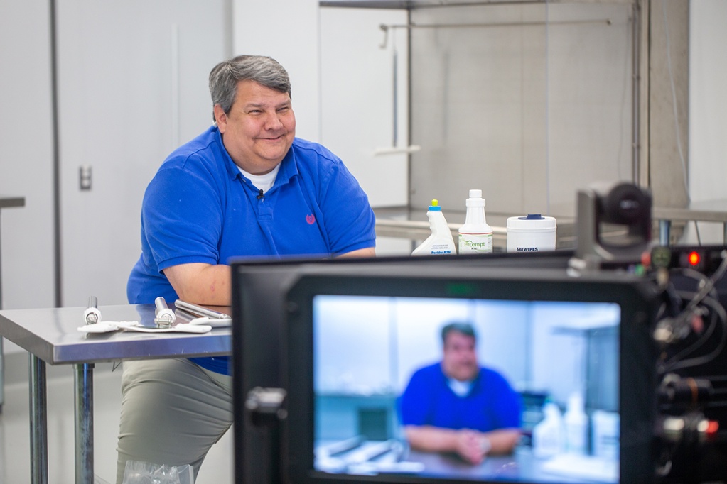 man in blue polo on video smiling 