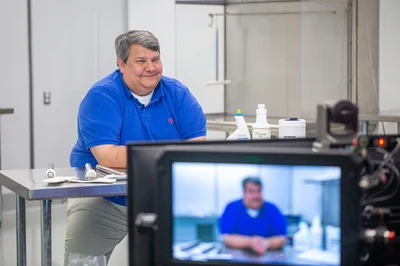 hombre con polo azul en video sonriendo